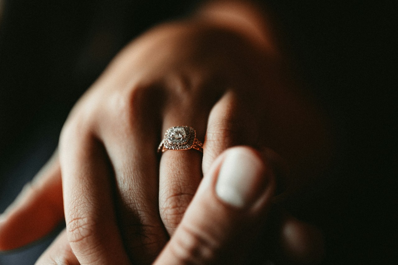 A close-up of a woman’s hand, adorned with rose gold double diamond halo engagement ring