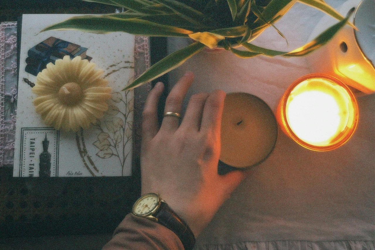 A woman’s hand holding a candle and wearing a gold ring and dress watch.