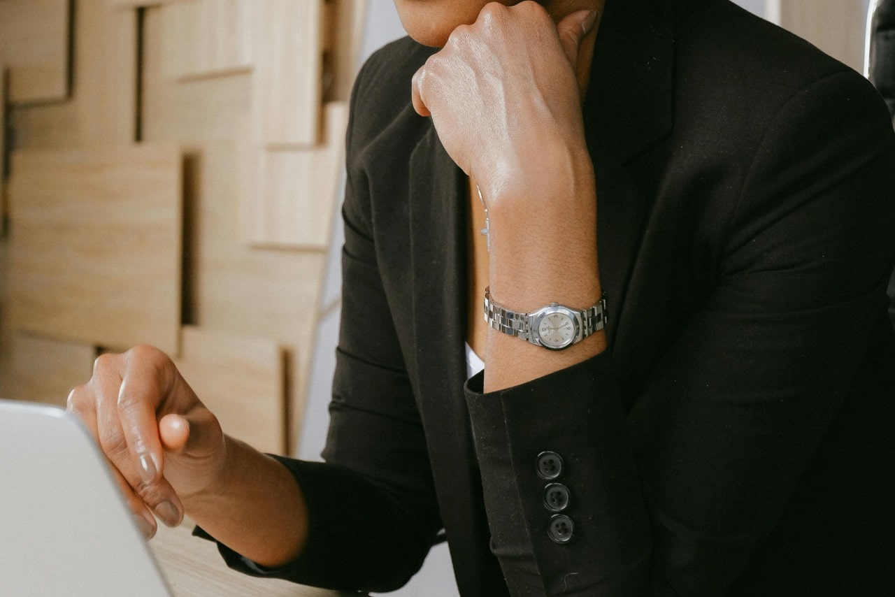 A woman looking at a computer and wearing a silver-toned dress watch.
