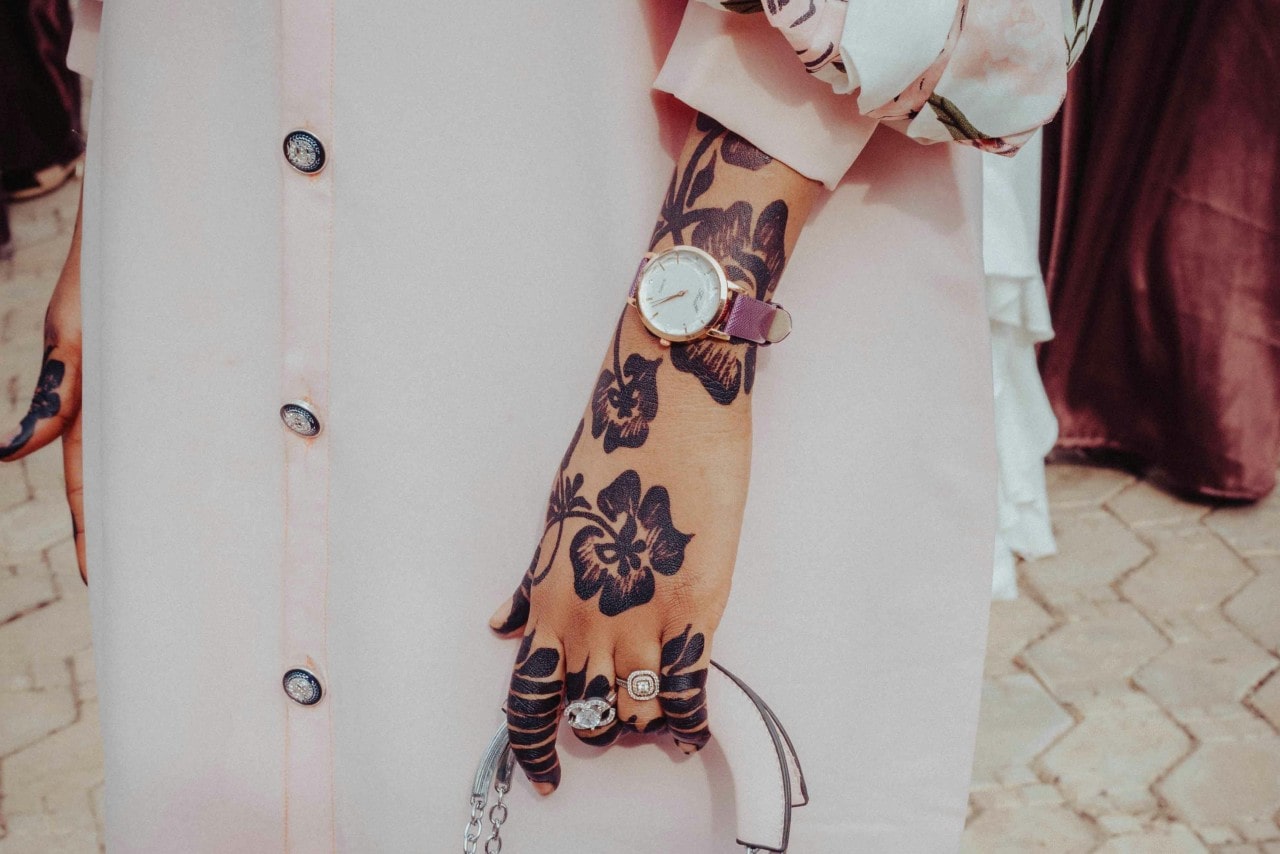 A tattooed woman wearing a gold and purple watch.