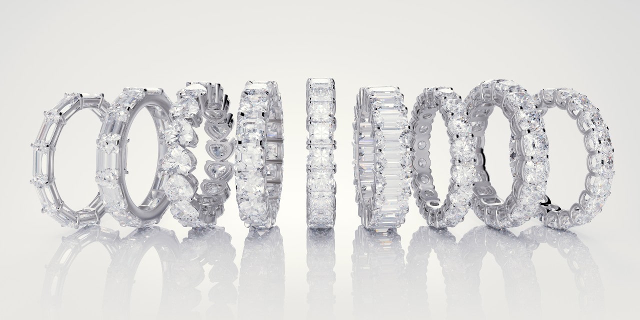 A row of eight elegant diamond rings in various settings displayed vertically on a reflective surface.