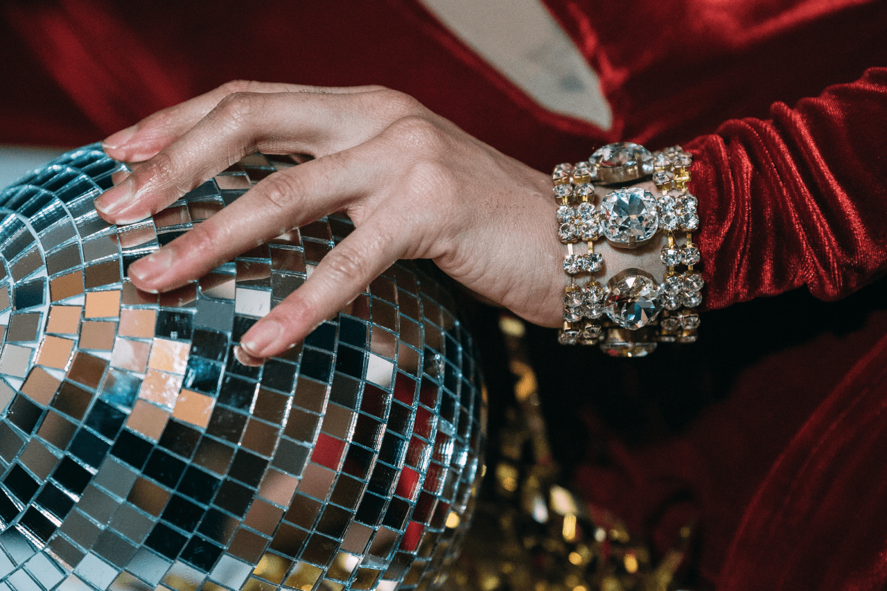 A woman’s hand grips a disco ball, showing off a chunky diamond bangle.