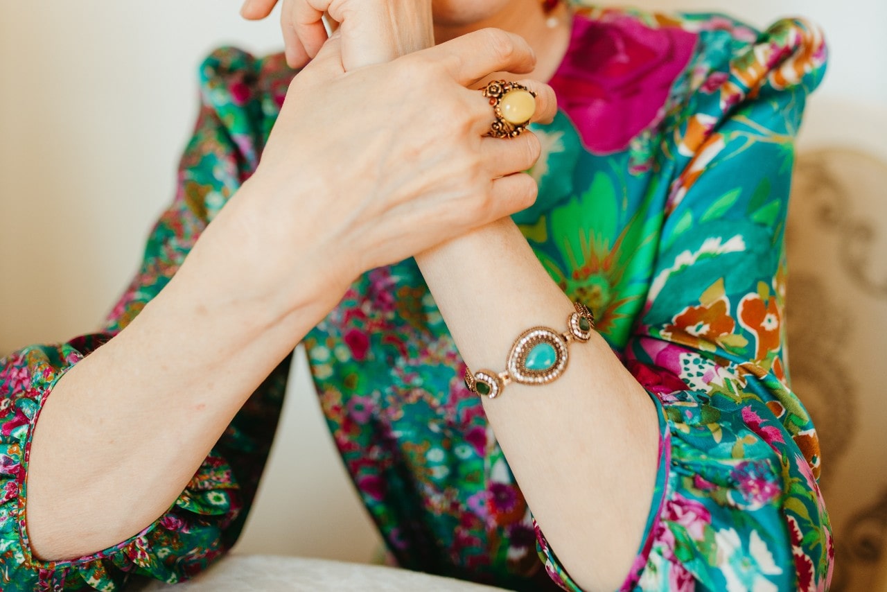 a woman in a bright patterned shirt wearing a bracelet featuring turquoise