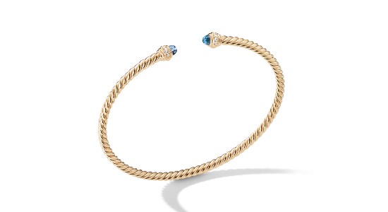 a yellow gold cuff bracelet with two small blue topaz gems