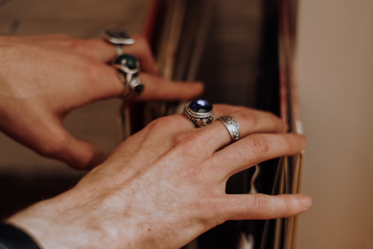 a pair of hands looking through a file folder and wearing a number of silver rings, one of which has a deep blue gemstone