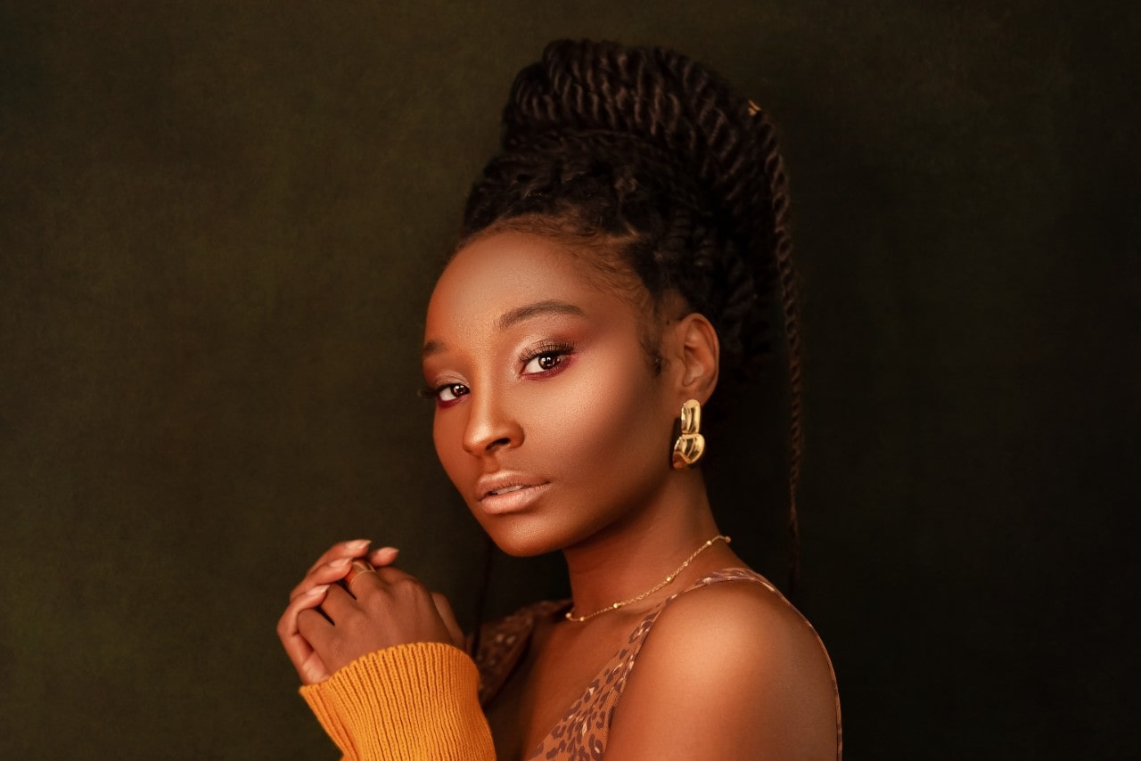 a woman looking into the camera and wearing bold gold earrings and a fine gold necklace