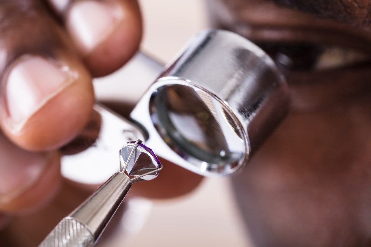 A gemologist inspects a faceted gemstone with a jeweler’s loupe.
