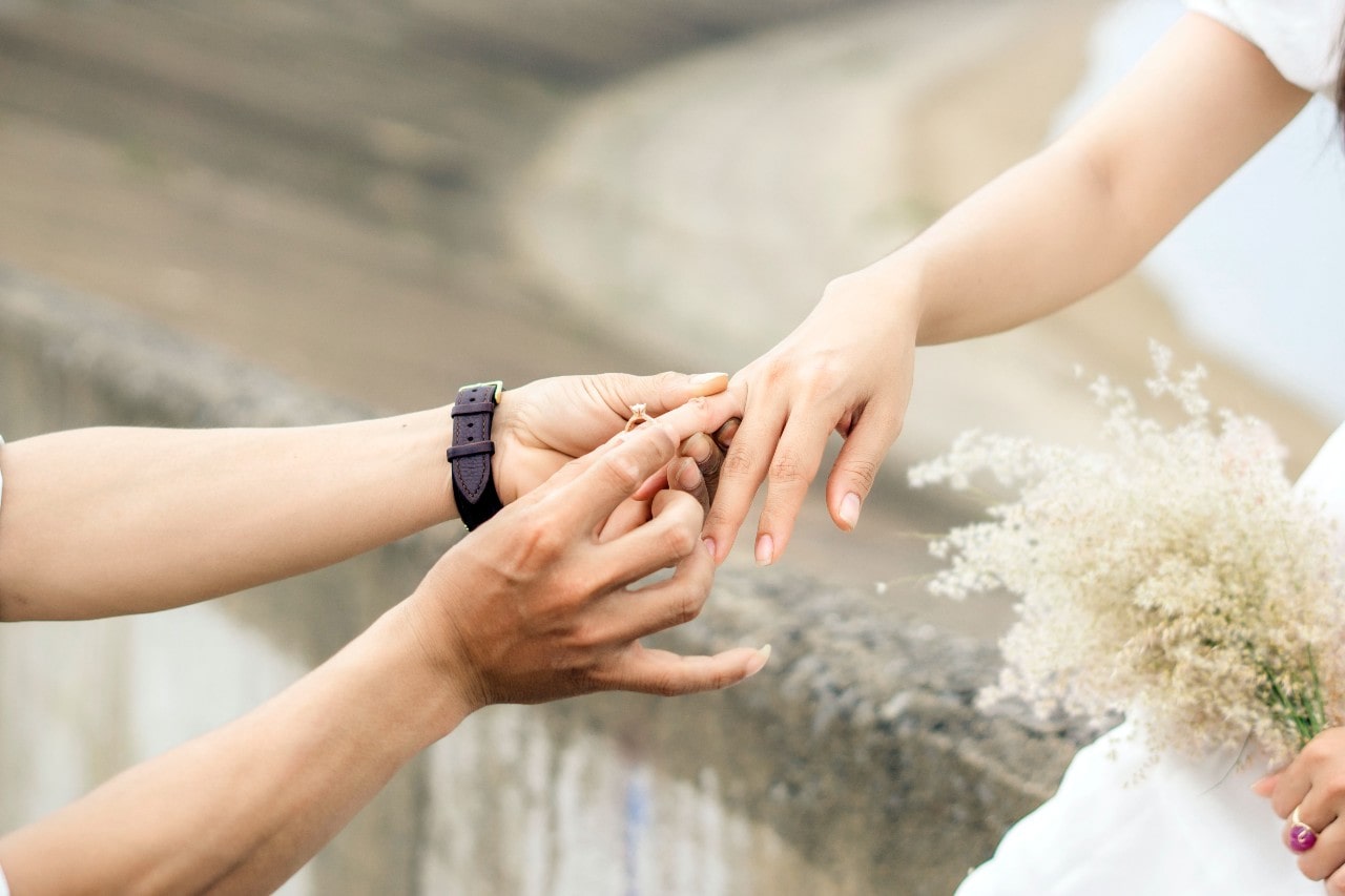 a man putting an engagement ring on the hand of a woman