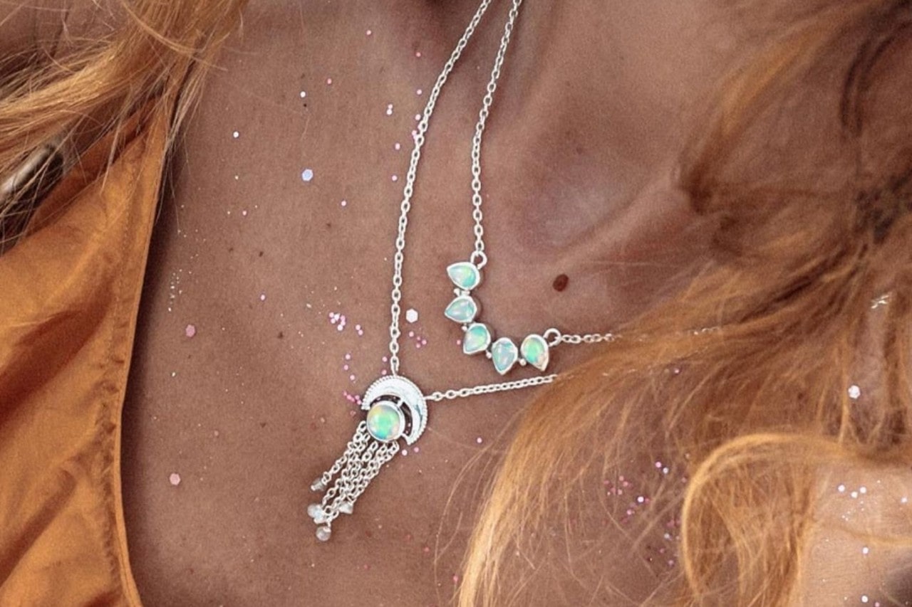 close up image of a woman’s neck adorned with two silver and opal necklaces