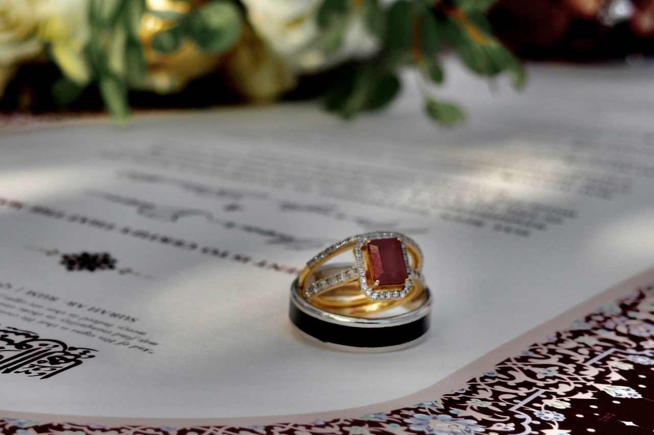 a stack of rings sitting on a wedding invitation