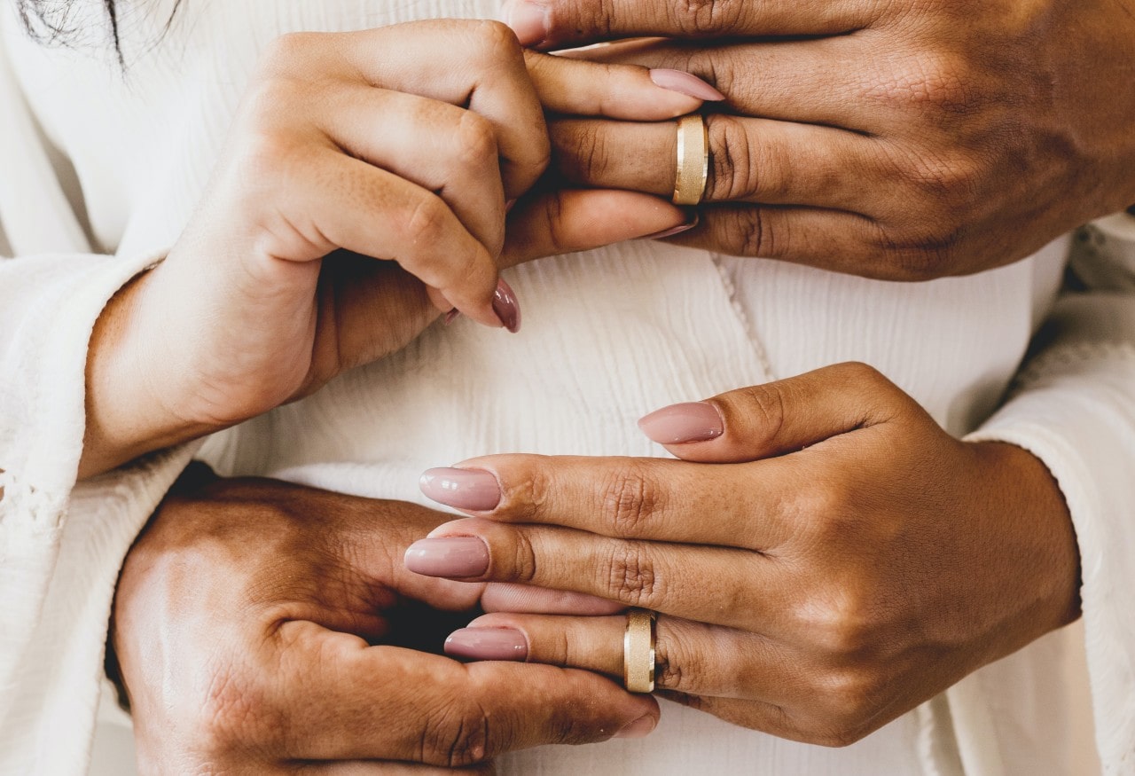a man and woman simultaneously placing matching bands on each others’ hands