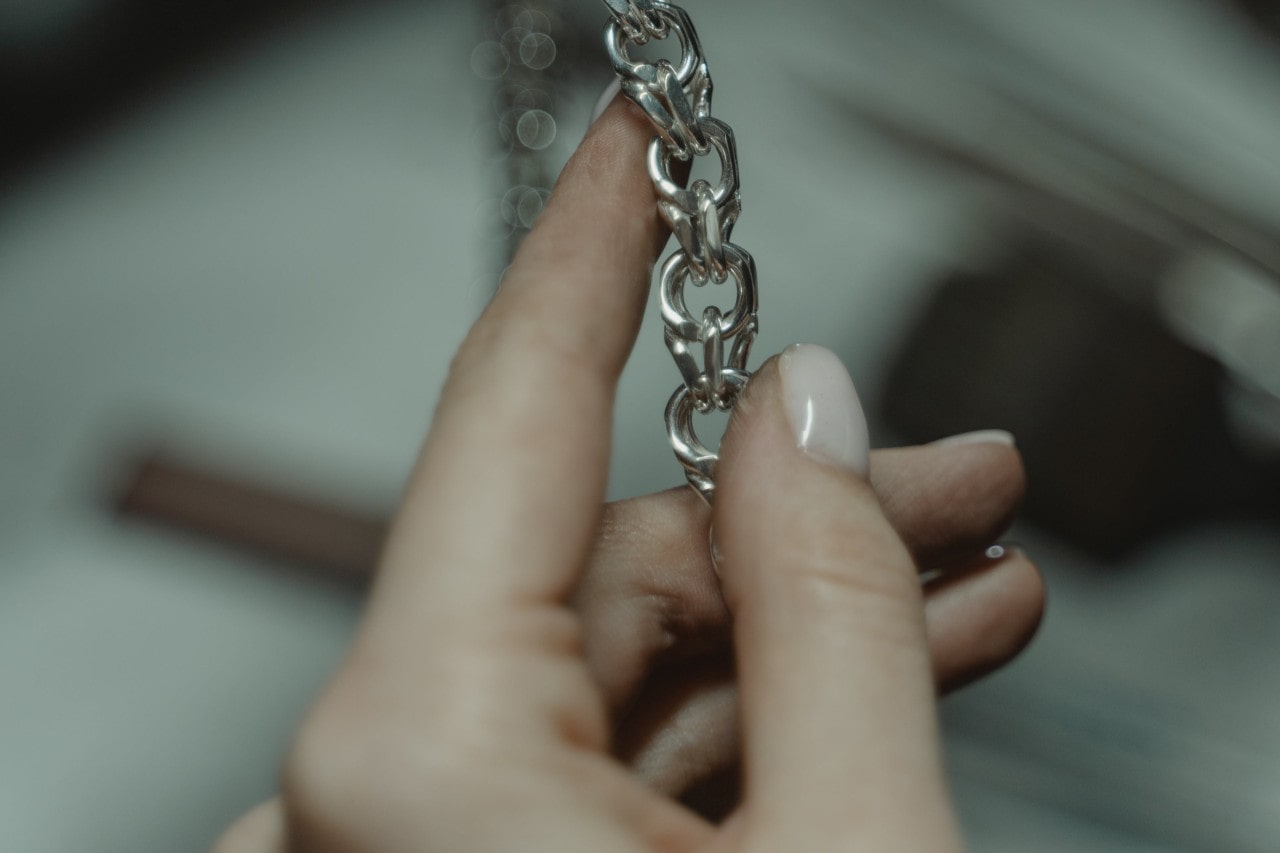 a professional jeweler holding a white gold chain for inspection