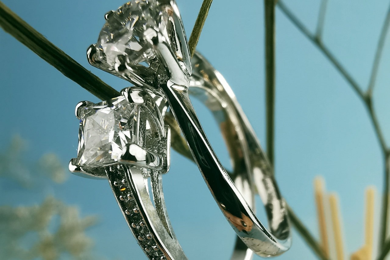 a pair of white gold diamond engagement rings against a sky blue background