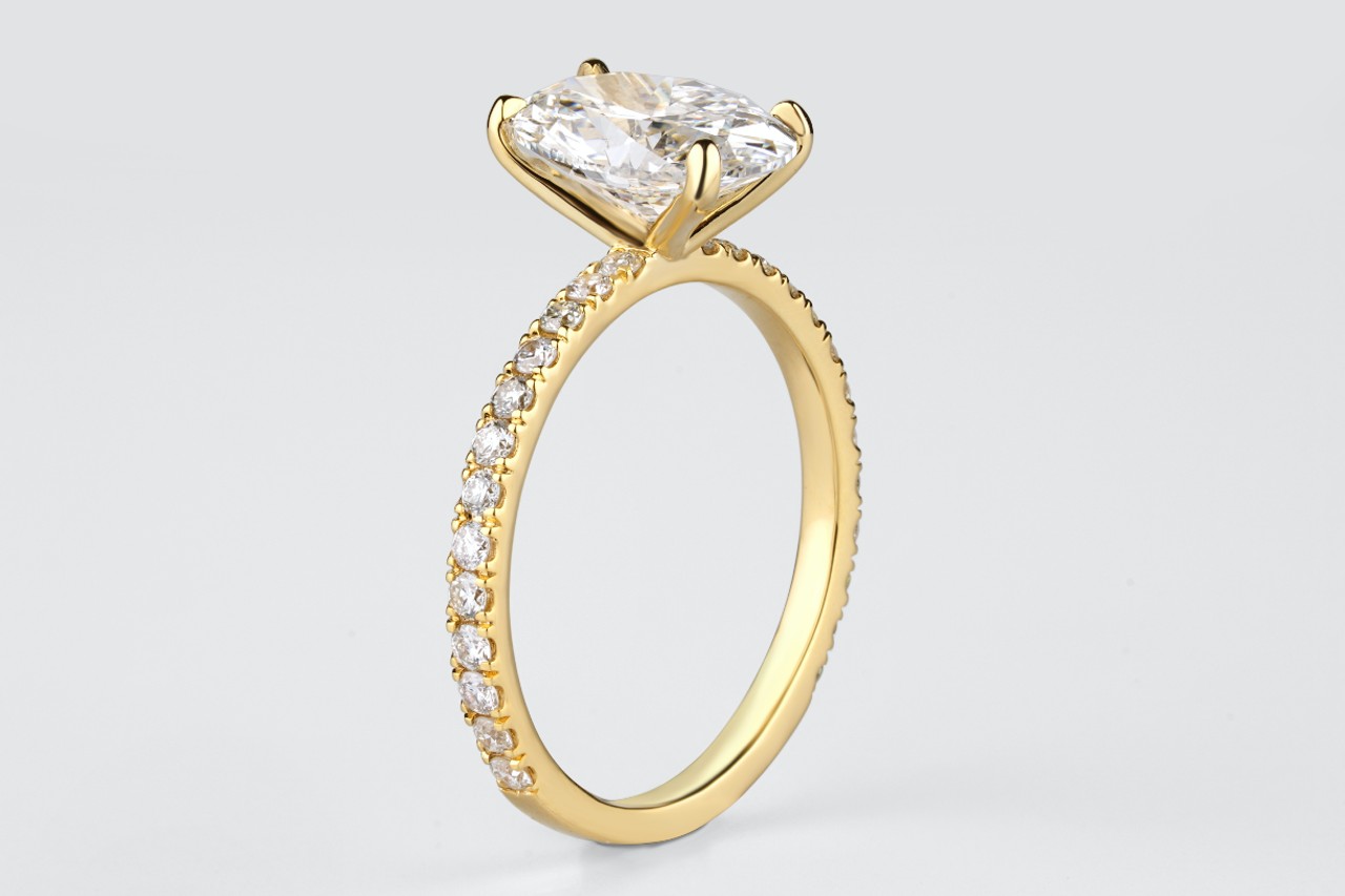 close up image of a gold engagement ring with an oval center stone and side stone details