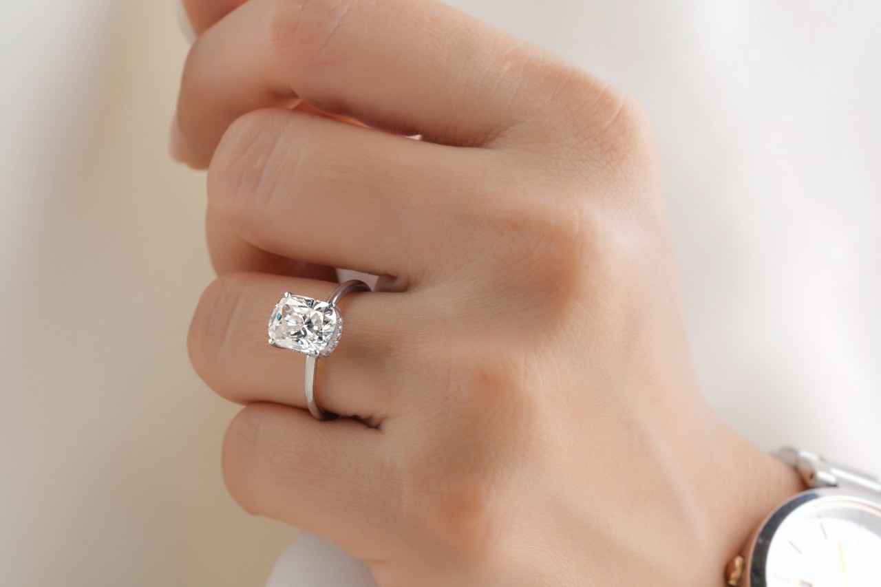 close up image of a woman’s hand wearing a solitaire engagement ring