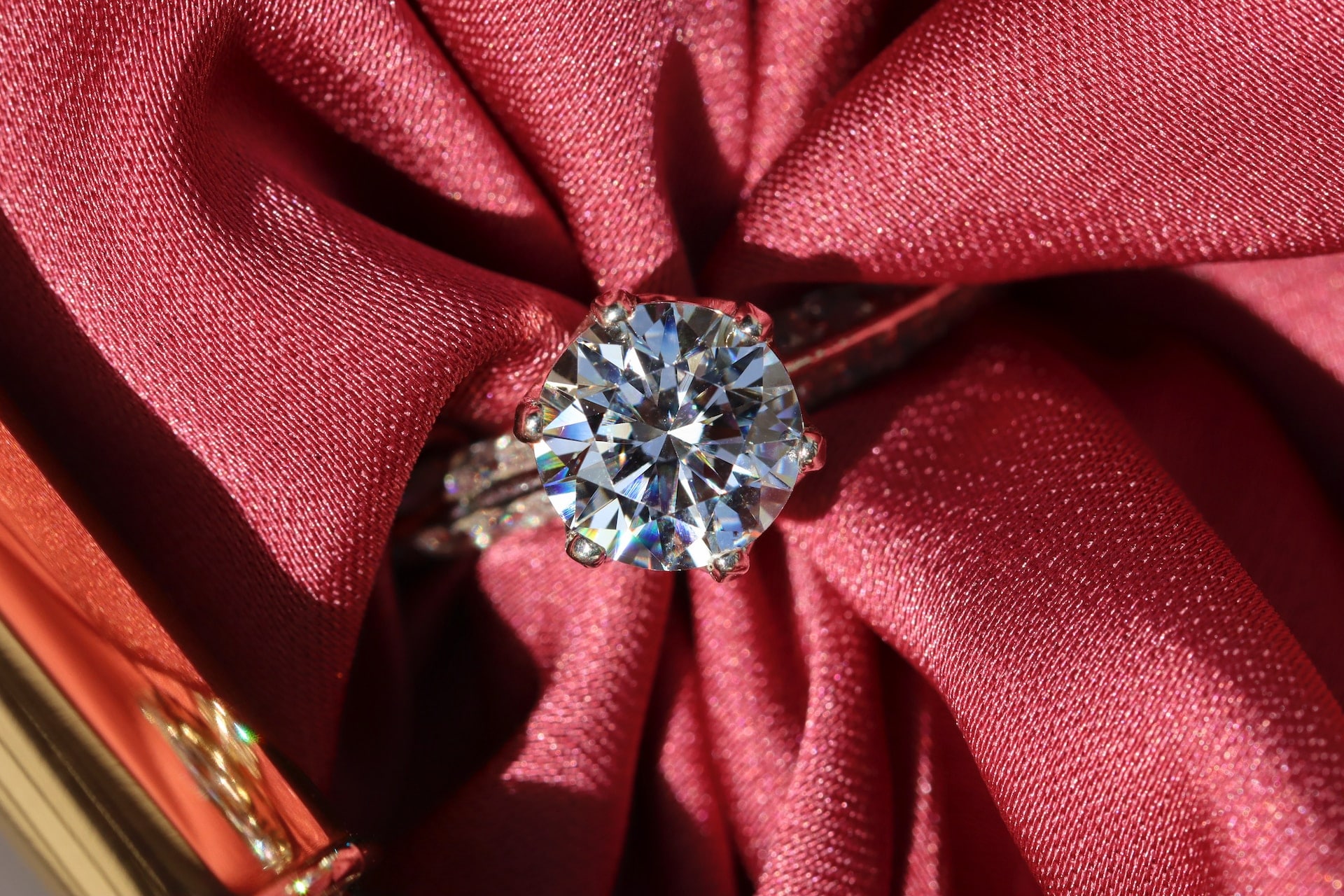 An engagement ring with round brilliant cut diamond atop of red fabrics