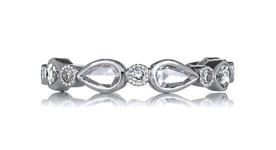 a white gold wedding band featuring round and pear shape diamonds in bezel settings