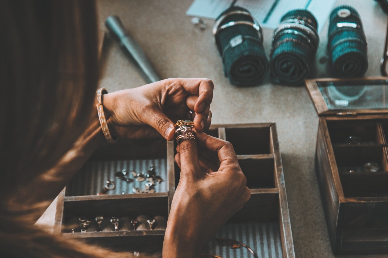 An over-the-shoulder view of a woman inspecting rings from her large jewelry collection.