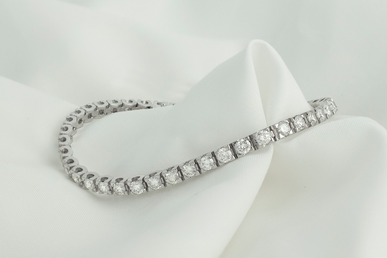 platinum and diamond bracelet resting on a white cloth background