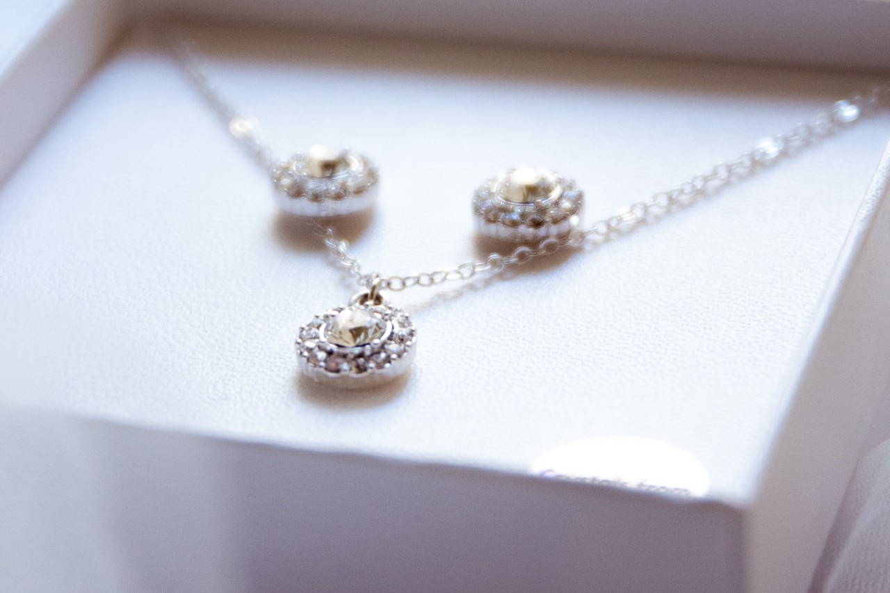Elegant silver jewelry set with a necklace and earrings, featuring circular designs with sparkling stones, displayed in a white box.
