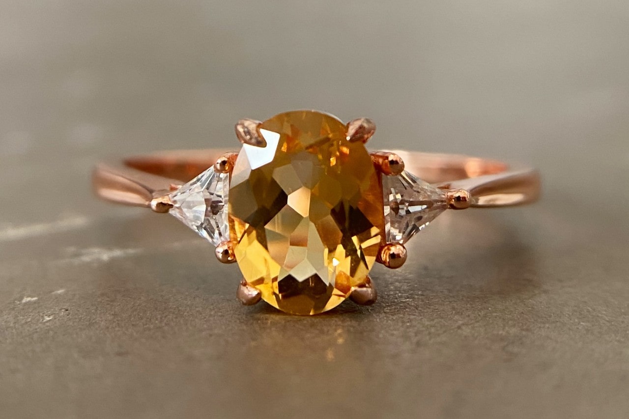a rose gold, three stone fashion ring featuring an oval cut citrine