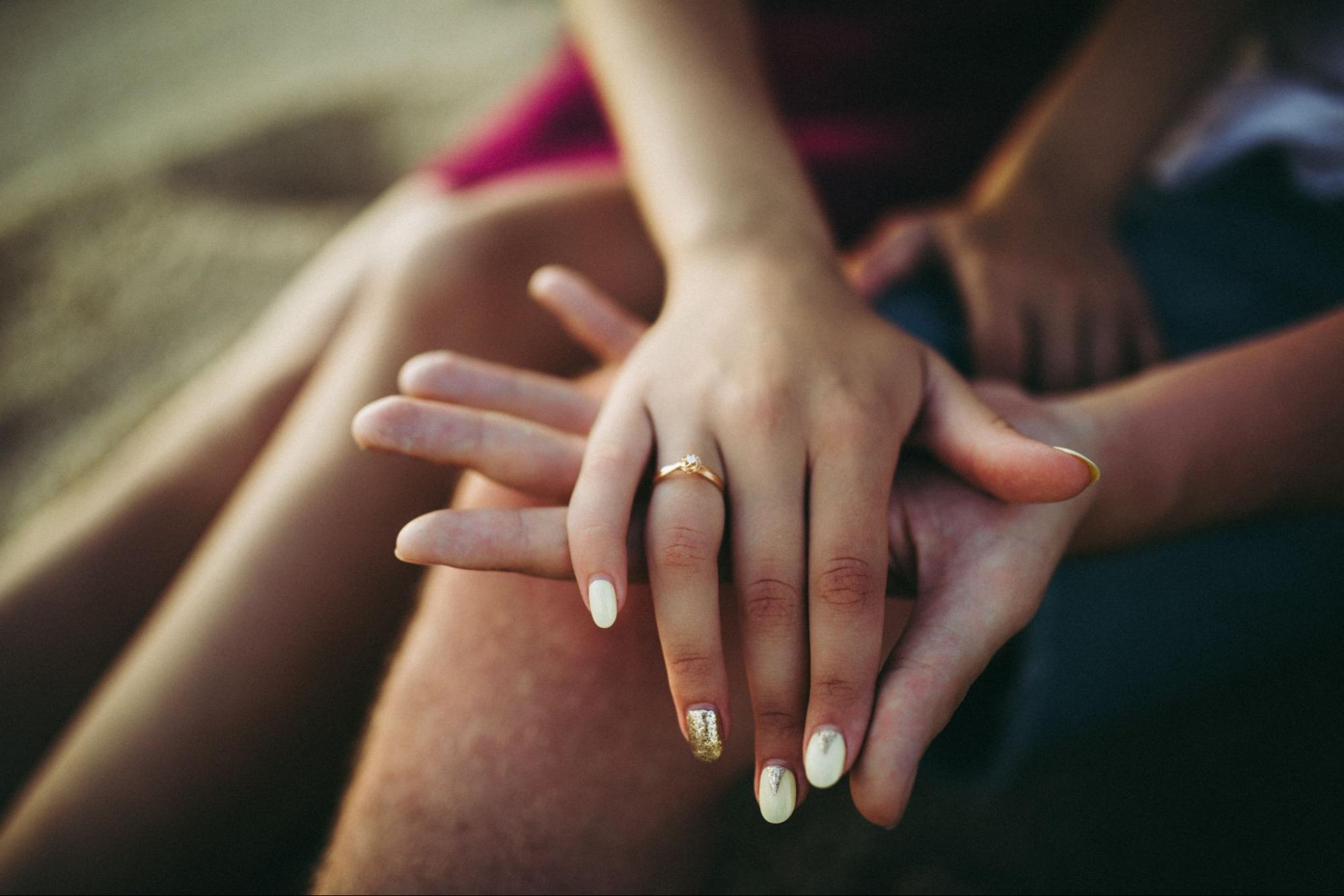 A couple shows off a small solitaire engagement ring.