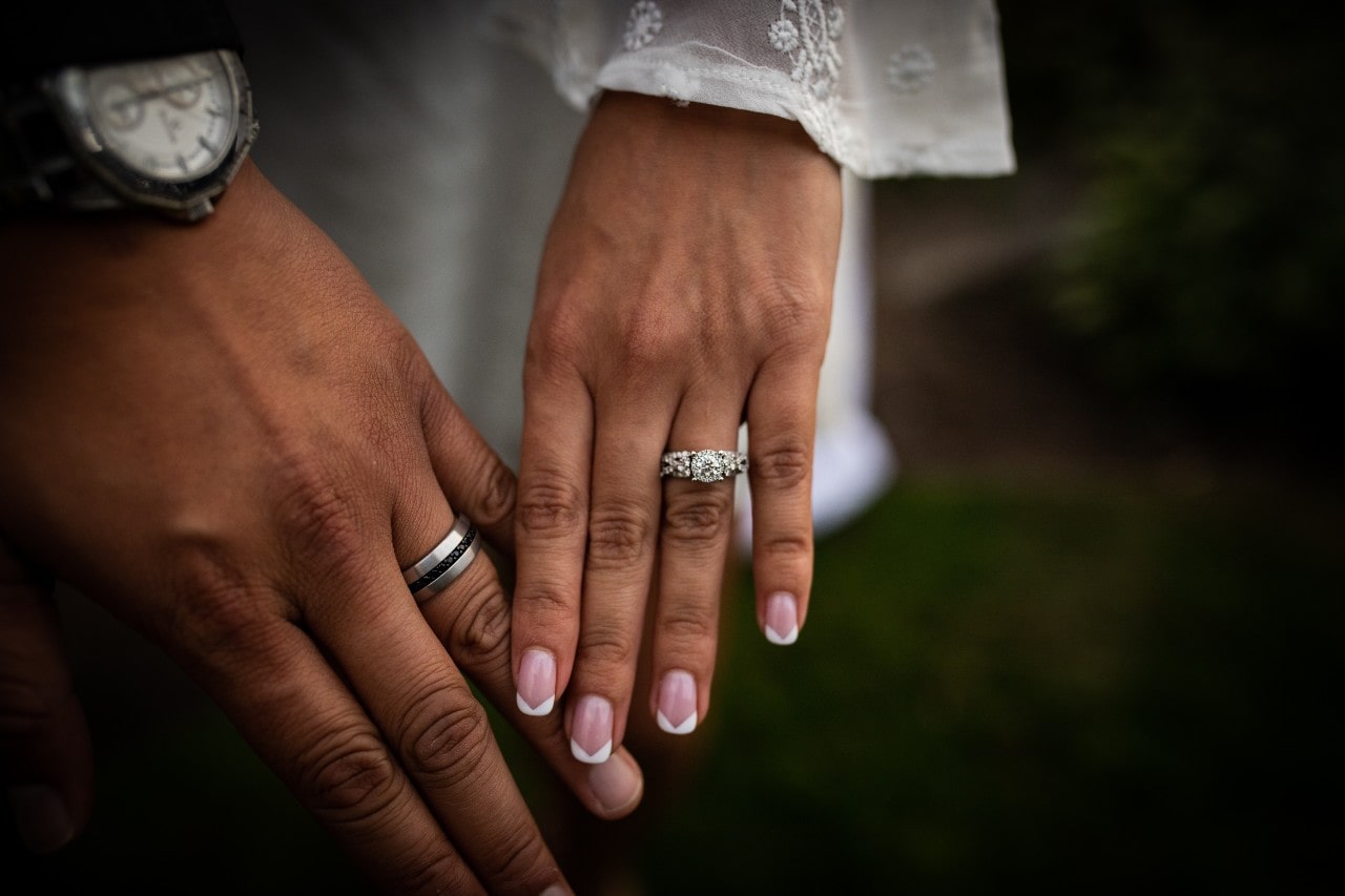 A bride wearing a detailed halo engagement ring with her groom. A bride wearing a detailed halo engagement ring with her groom.