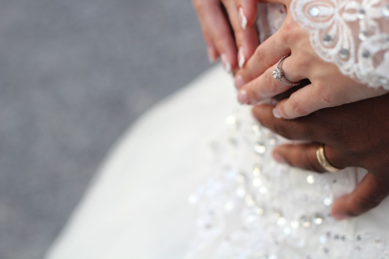 A bride and groom embracing, a close up of their hands wearing wedding rings. A bride and groom embracing, a close up of their hands wearing wedding rings.