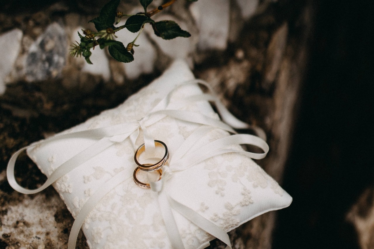 two wedding bands sit on a white ring bearer's pillow.