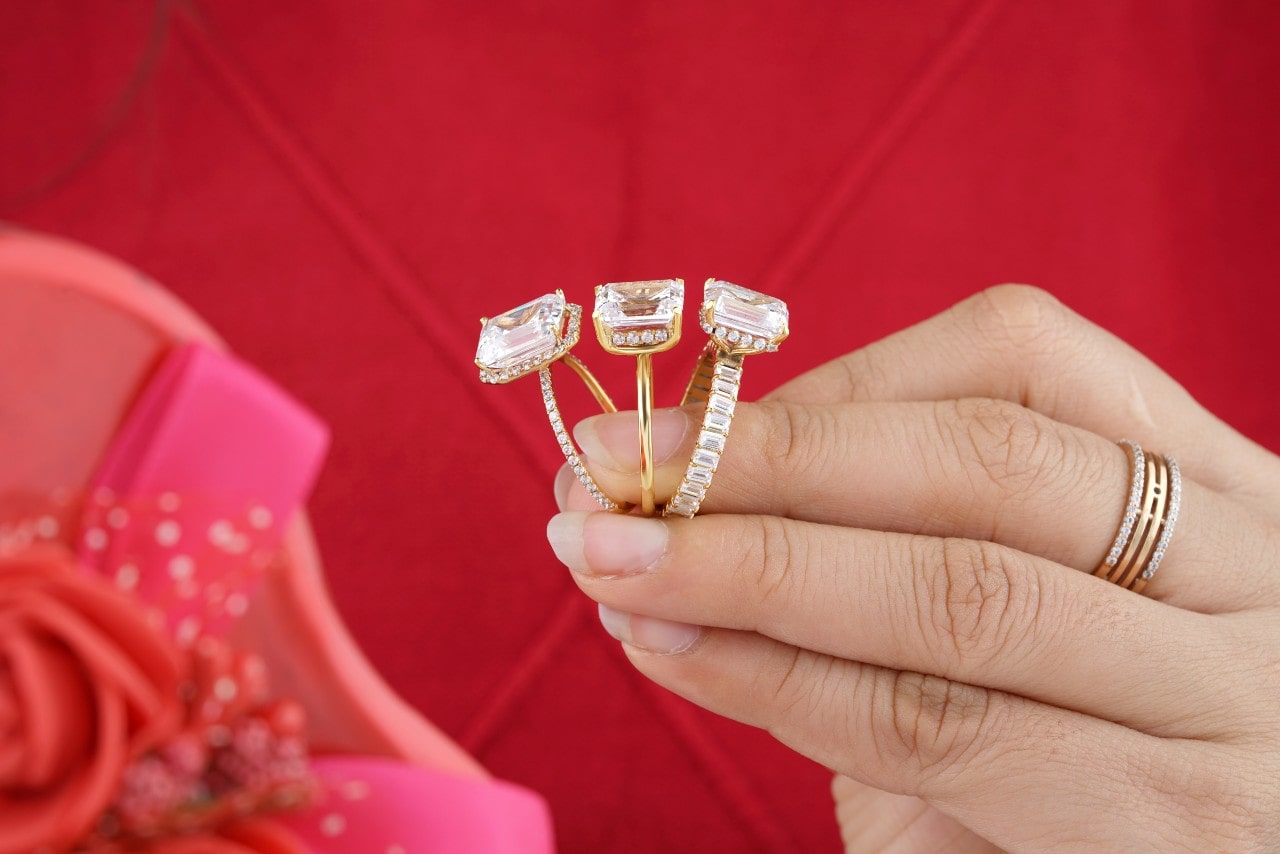 A woman holds three gold engagement rings. A woman holds three gold engagement rings.