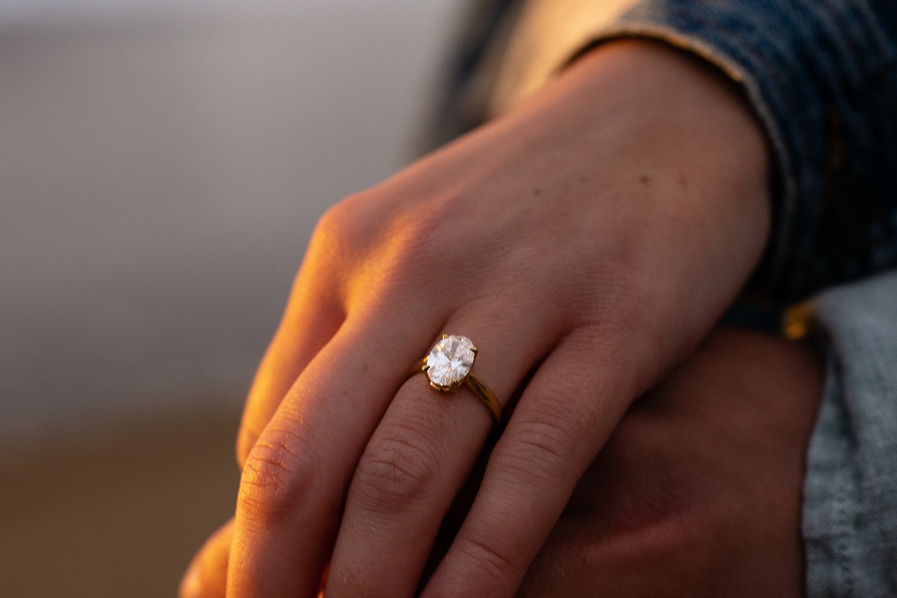 A woman wears a gold solitaire engagement ring. A woman wears a gold solitaire engagement ring.