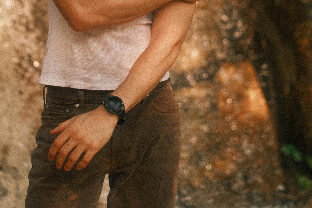 A man in a white shirt and brown pants and a black watch standing outdoors. A man in a white shirt and brown pants and a black watch standing outdoors.
