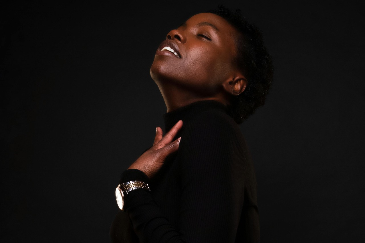 A woman dressed in black and touching her shoulder wearing a stainless steel watch. A woman dressed in black and touching her shoulder wearing a stainless steel watch.