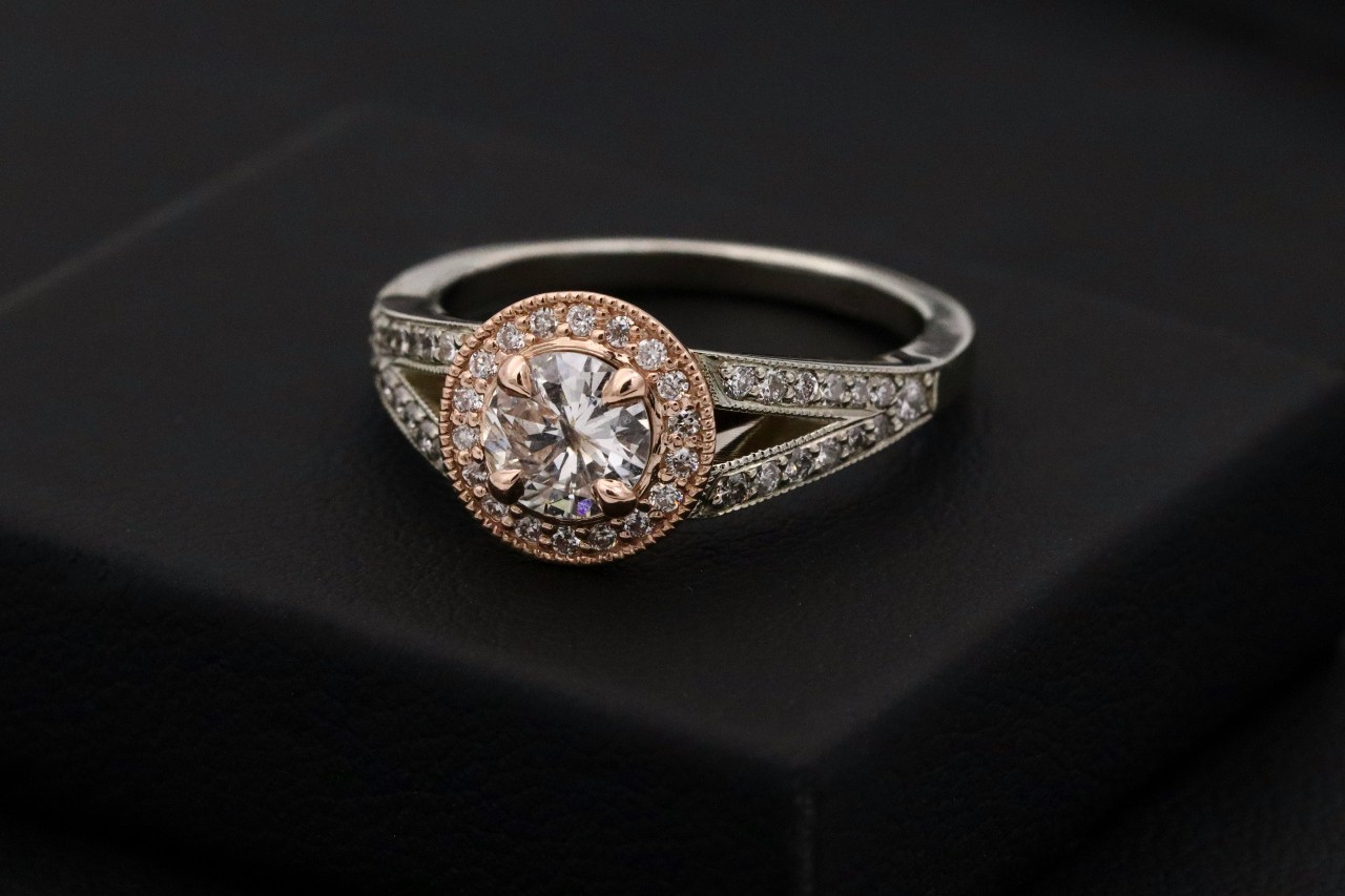 A vintage halo engagement ring sits on a black display.