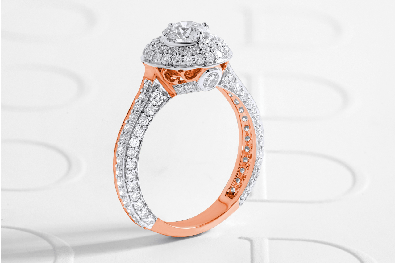 A rose gold and white gold engagement ring sits on an embossed paper.