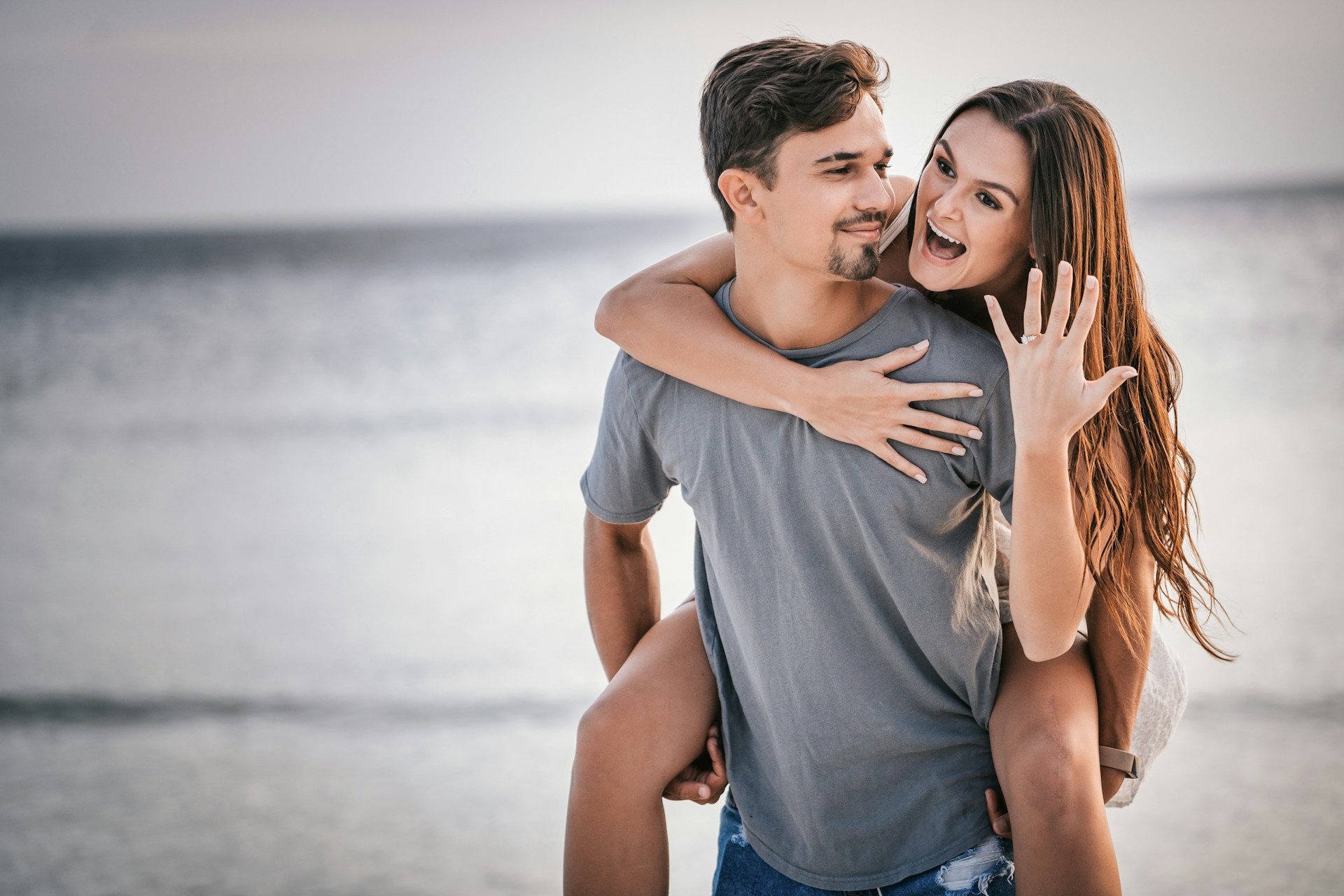 A young couple celebrate their recent engagement on a beach.