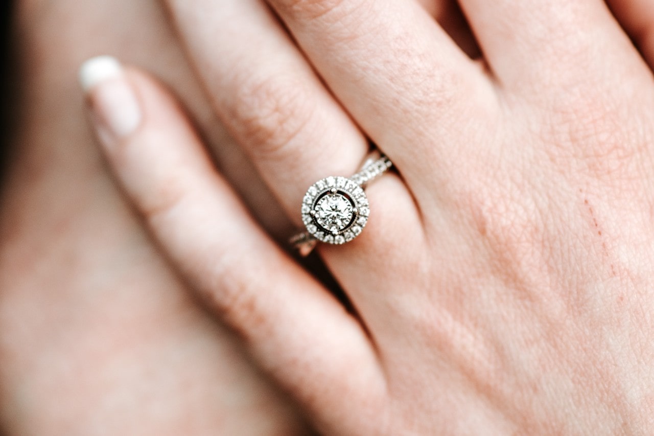 a halo two tone engagement ring on a woman’s hand.